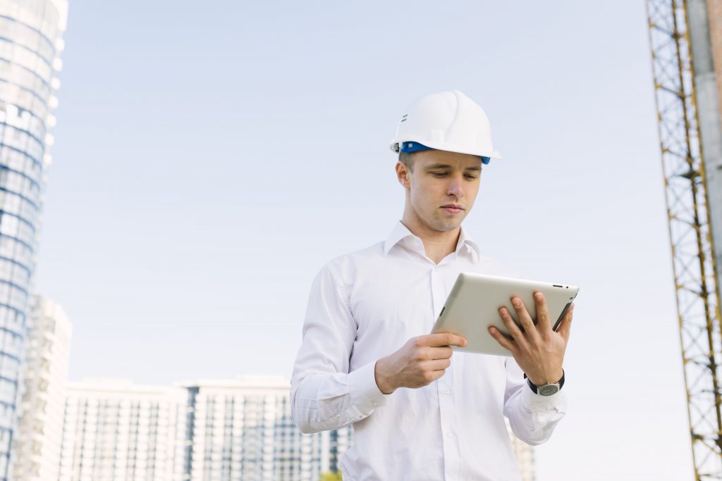 An industrial worker looking his tablet at industrial site.